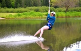 woman landing in lake from zipline