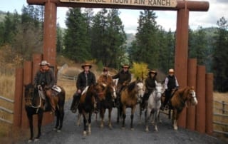 horseback riders posing at ranch entrance