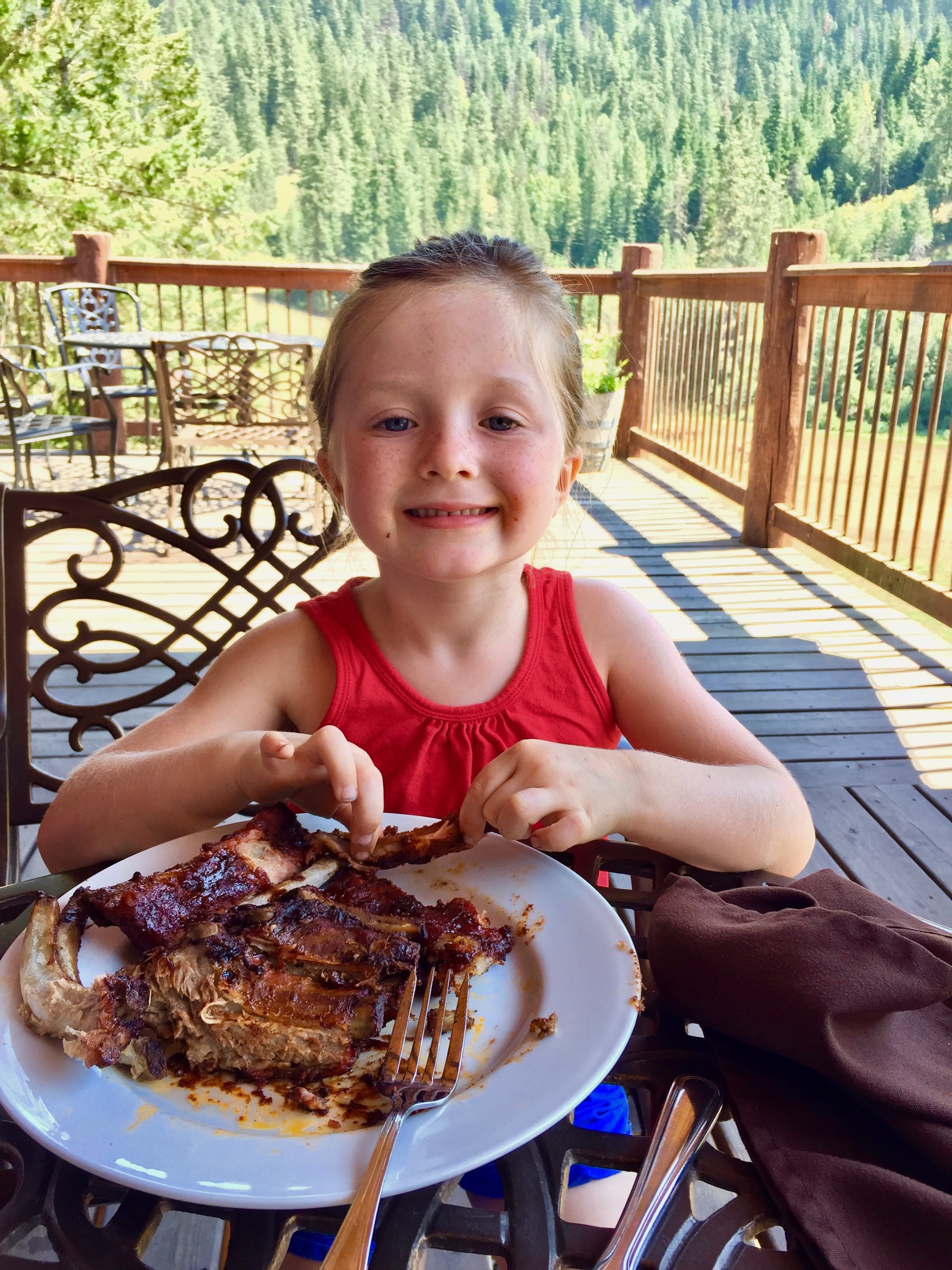 Young girl eating ribs.