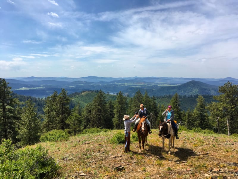 Two women on horseback on a hilltop vista.
