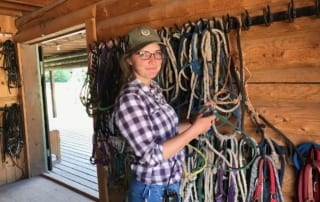 Team member checking reins while working her summer ranch job at RHMR.