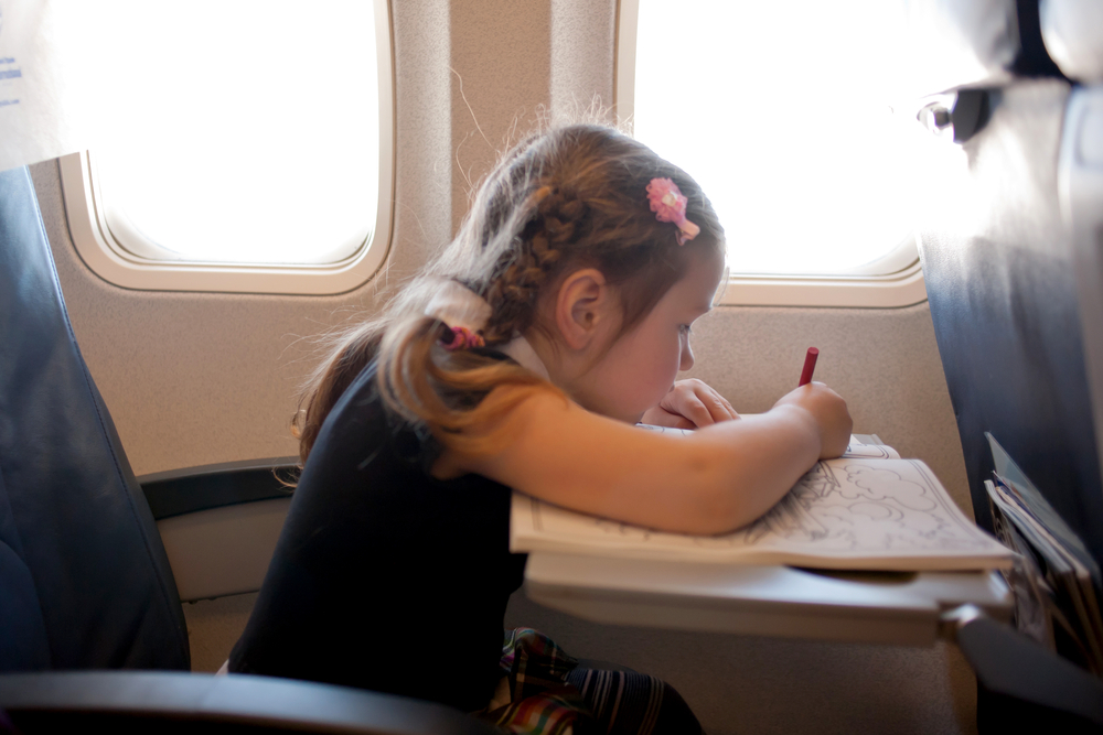 Young girl coloring while on an airplane