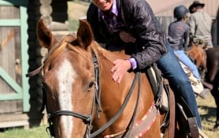 An avid horseback rider gleeful pats their trusty steed while enjoying a singles retreat.