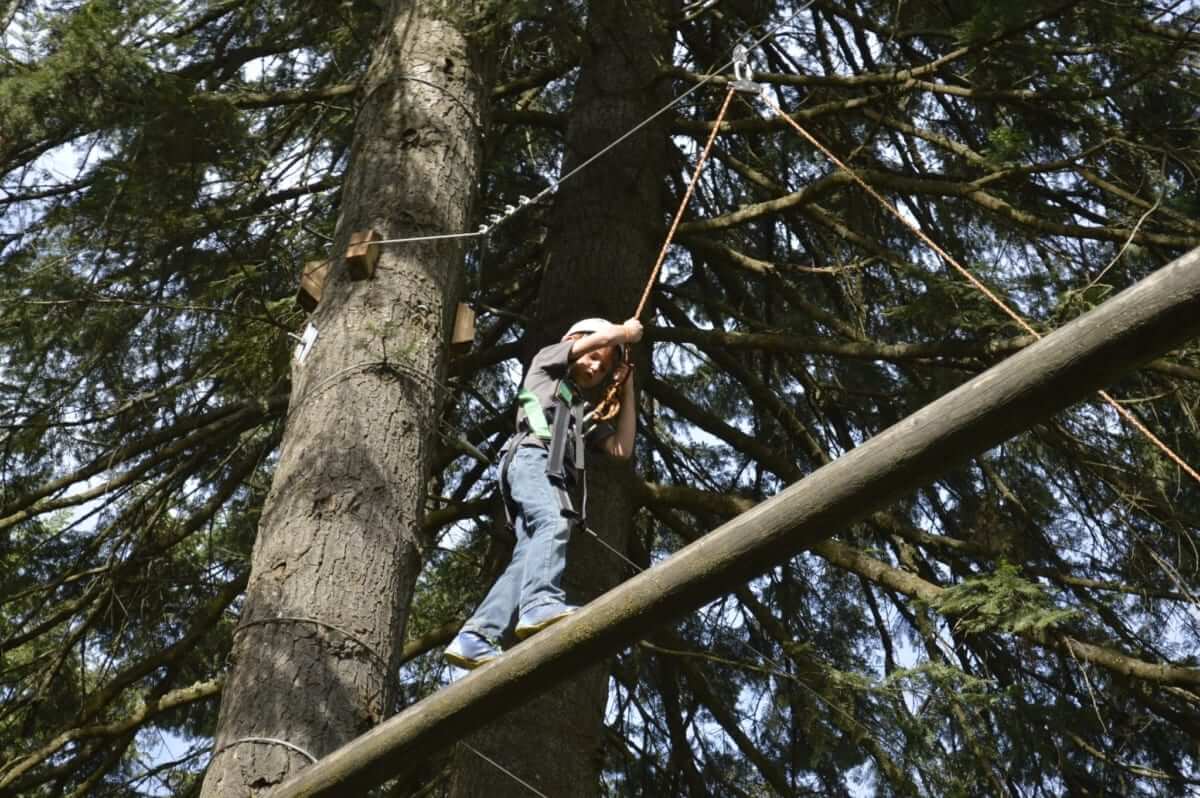 A young adventurer scales the challenge course at Red Horse Mountain Ranch during a family summer vacation.