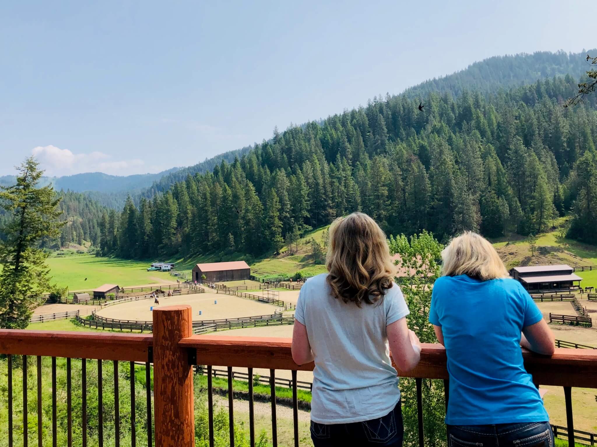 A pair of female relatives gaze at a nearby mountain during their ranch family reunion.