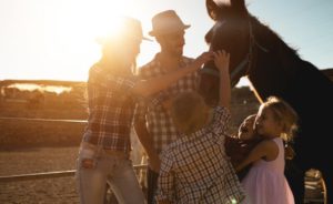 A young family enjoys the company of a horse during the mountain ranch vacation.