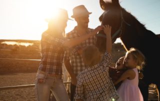 A young family enjoys the company of a horse during the mountain ranch vacation.