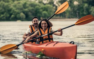 Romantic Dude Ranch Vacation: A young couple kayaks along a calm lake in Idaho.