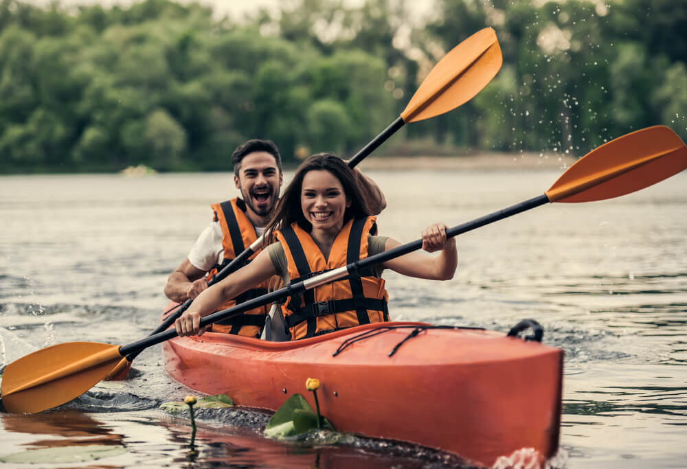 Romantic Dude Ranch Vacation: A young couple kayaks along a calm lake in Idaho.